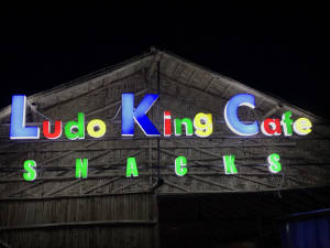 竹建築上 Ludo King Cafe Snacks 的彩色霓虹招牌（夜間）。