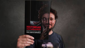 男子手持恐怖書籍《Historias Perturbadoras》，封面詭異。