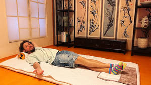 男子在傳統日式房間的榻榻米上休息，配有竹飾。 — 日本 壁紙