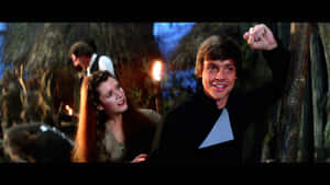 Luke Skywalker 在夜晚的叢林營地中，在Leia Organa旁邊舉起拳頭慶祝。