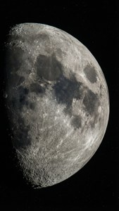 月球坑坑洼洼的表面特寫，背景是繁星點點的夜空。