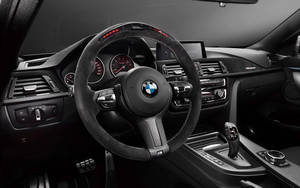 黑色BMW M汽車內飾，帶有紅色發光儀表和碳纖維飾條。