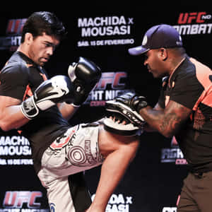 UFC拳手在比賽中執行高踢，裁判在附近監視。