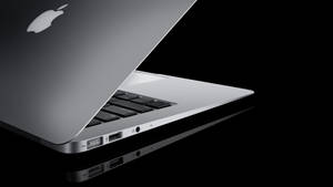 銀色MacBook手提電腦在黑色反光表面上顯示連接埠。
