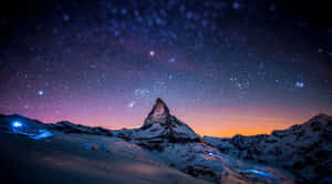 星空暮色天空下的白雪覆蓋的山峰，下方有發光的藍色燈光。