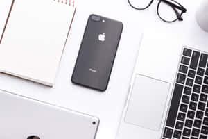 整潔現代的桌面，配有手提電腦、iPhone、筆記本和眼鏡