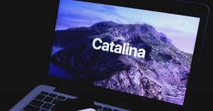 手提電腦顯示 macOS Catalina 啟動畫面，帶有山脈壁紙。