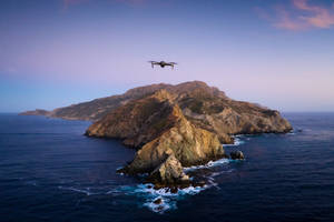 無人機在黃昏時飛越岩石島嶼，海浪拍打。