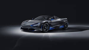 在黑暗的攝影棚環境中，一輛帶有藍色燈光點綴的啞光灰色McLaren 720S Spider。