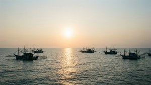 漁船在平靜海面上以金色夕陽為背景的剪影