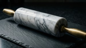 帶黃銅手柄的大理石擀麵杖放在深色石板表面上。
