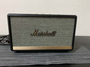 Marshall便攜式揚聲器放在灰色墊上，背景為白牆