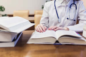 醫生在辦公室的木桌上查閱醫學書籍。