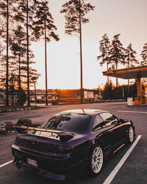 黑色跑車停在加油站，金色夕陽，松樹