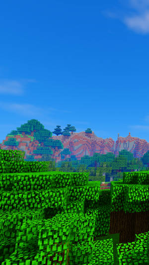 藍天下有綠色樹木和紅色山脈的Minecraft遊戲場景
