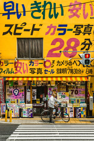 踩單車的男子經過有紅色交通燈的彩色日本相片店。