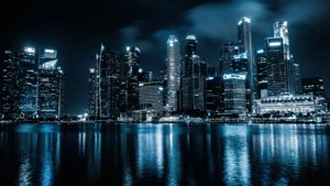 夜間城市景觀，燈火通明的摩天大樓倒映在水中。
