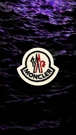 Moncler 標誌布章在深色波浪紫色銀河背景上。