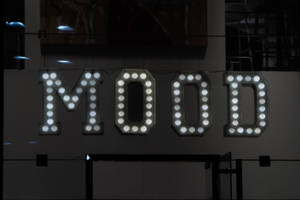 在黑暗的城市環境中，發光的白色字母標誌拼出MOOD。