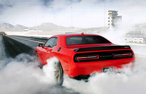 紅色 Dodge Challenger SRT 在直線加速賽道上進行燒胎，冒出煙霧。