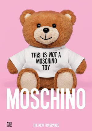 一隻棕色泰迪熊穿著寫有「This is not a Moschino toy」的T恤，背景為粉紅色。 — 泰迪熊 壁紙