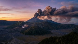 火山在黎明時分噴發灰雲，籠罩山區景觀