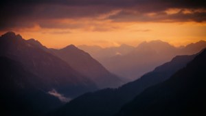 日落時分的山脈，橙色天空和霧氣山谷