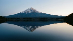 富士山頂白雪在平靜湖面上的黎明倒影