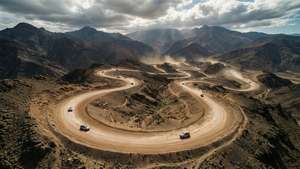越野車在多雲天空下穿過乾燥山脈的蜿蜒土路。
