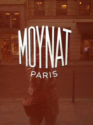 一個人的倒影和Moynat Paris標誌在帶有水平百葉窗的玻璃商店櫥窗上。 — 巴黎 壁紙