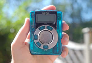 手在戶外陽光下拿著藍色數碼MP3播放器。 — 音樂美學 壁紙