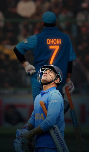 身穿藍色球衣的板球運動員在夜間球場上仰望隊友Dhoni。
