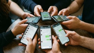 一群人圍著木桌使用智能手機發送訊息。