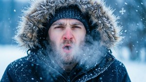 男人裹著冬季外套在飄雪中呼氣。