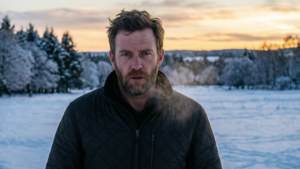 穿冬季外套的男人站在日落時分的雪地上