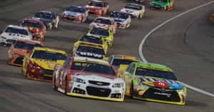 NASCAR賽車在明亮的燈光下夜間在賽道上高速飛馳。