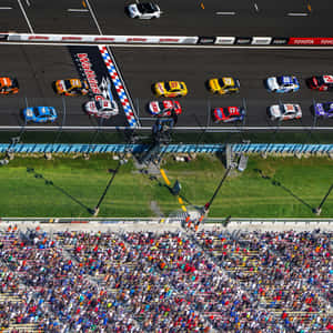 NASCAR賽車在馬丁斯維爾賽道衝過終點線，粉絲們歡呼雀躍。 — iPad Air 11 壁紙