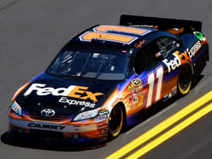 FedEx Express Toyota Camry 賽車在賽道上疾馳，帶有黃色線條。