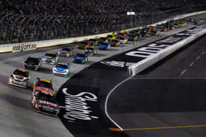 夜間NASCAR比賽，賽車在明亮燈光下於賽道上飛馳。