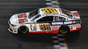 一輛編號88的NASCAR賽車在夜間賽道上飛馳。