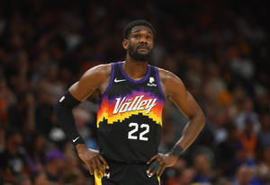 身穿Suns球衣的籃球運動員雙手叉腰站立比賽中。