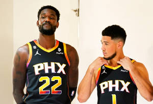 兩位鳳凰城太陽隊籃球運動員身穿隊服在室內擺姿勢。