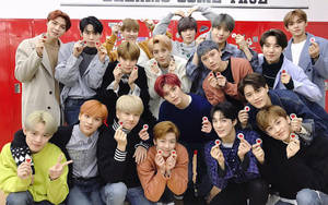 K-pop組合在紅色儲物櫃前手持心形糖果擺姿勢。