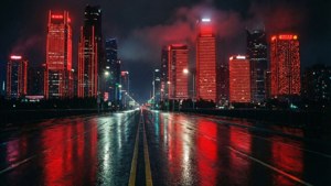 夜晚潮濕的城市街道，在烏雲下反射高樓的紅色霓虹燈光