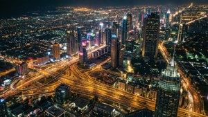 繁華城市的夜間航拍，燈火通明的摩天大樓和發光的高速公路。