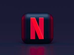 一個3D Netflix標誌立方體，在深色反光表面上帶有紅色字母N。 — Netflix GIF 壁紙