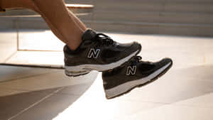 特寫鏡頭：黑色New Balance運動鞋中的腳懸浮在陽光照射的路面上方。