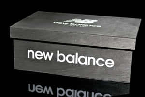 黑色New Balance鞋盒，帶有白色標誌，位於反射表面上。