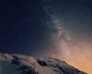 在繁星點點的夜空下，白雪覆蓋的山峰，銀河清晰可見。