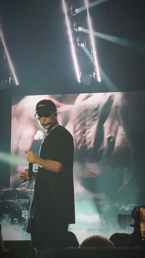 一位音樂家在明亮的燈光下，身後有一個大屏幕，在舞台上表演。
